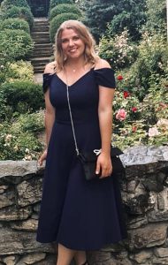 Frau im dunkelblauen Kleid vor Steintreppe und blühendem Garten, Logistik Saalfelden